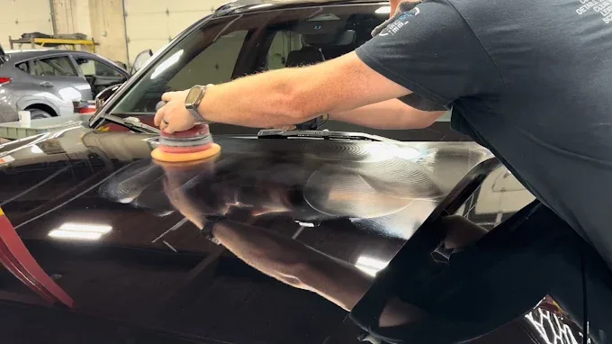 Technician using DA polisher on black car hood during paint correction — Blue Rose Detailing Springfield OR
